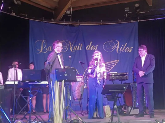 Vendredi 21 mars 2025. Pérols (34), La Nuit des Ailes, Nathalie chante « La Marseillaise » et « J’ai deux amours » entourée de monsieur le maire Jean-Pierre Rico et de monsieur Jean-Marc Leiendeckers, président de l’association de l’Hérault.